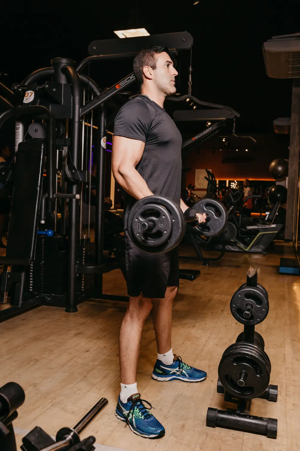 An athlete performing a standing barbell curl