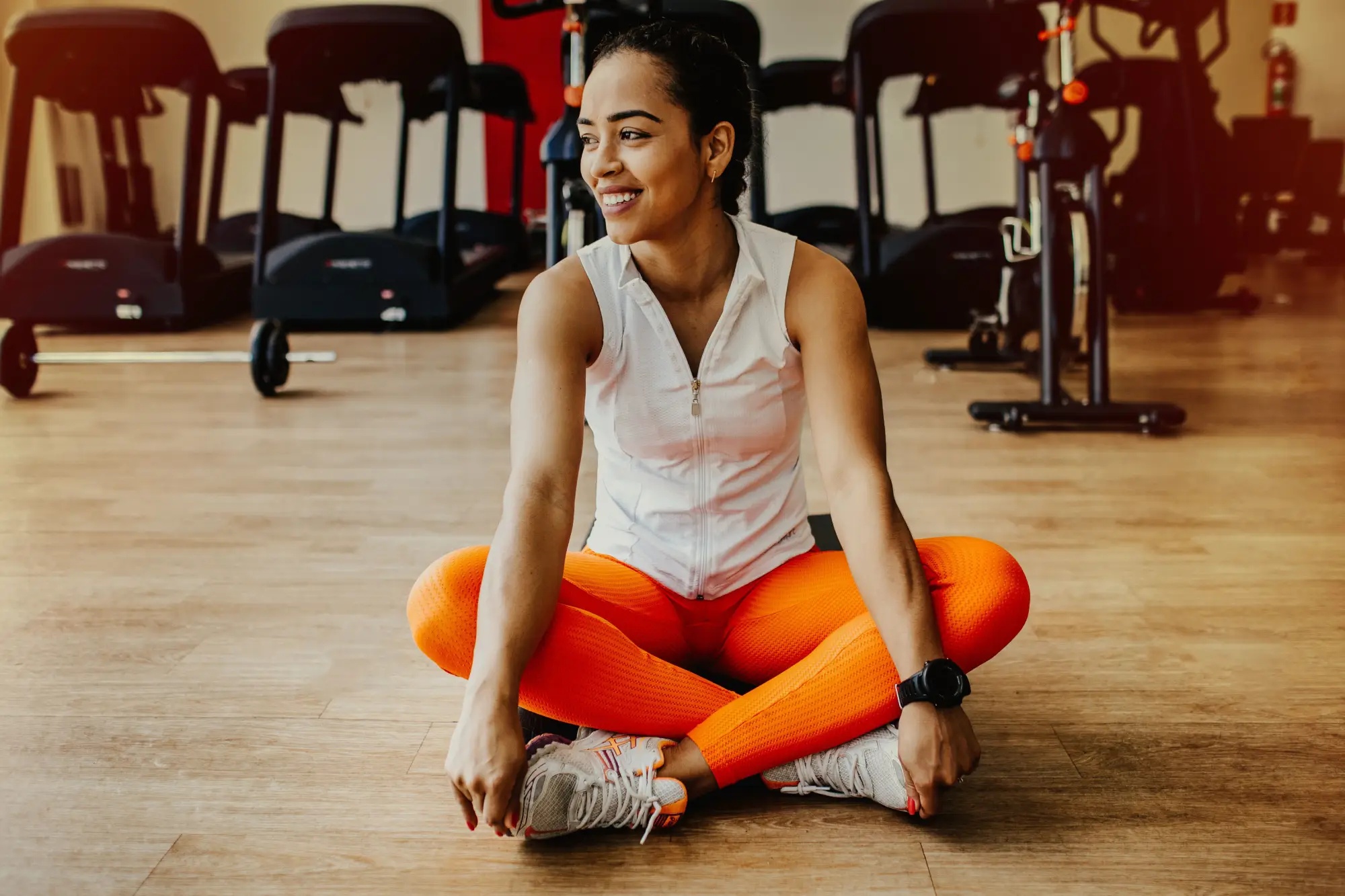 A woman sitting cross-legged on a gym floor between training sessions